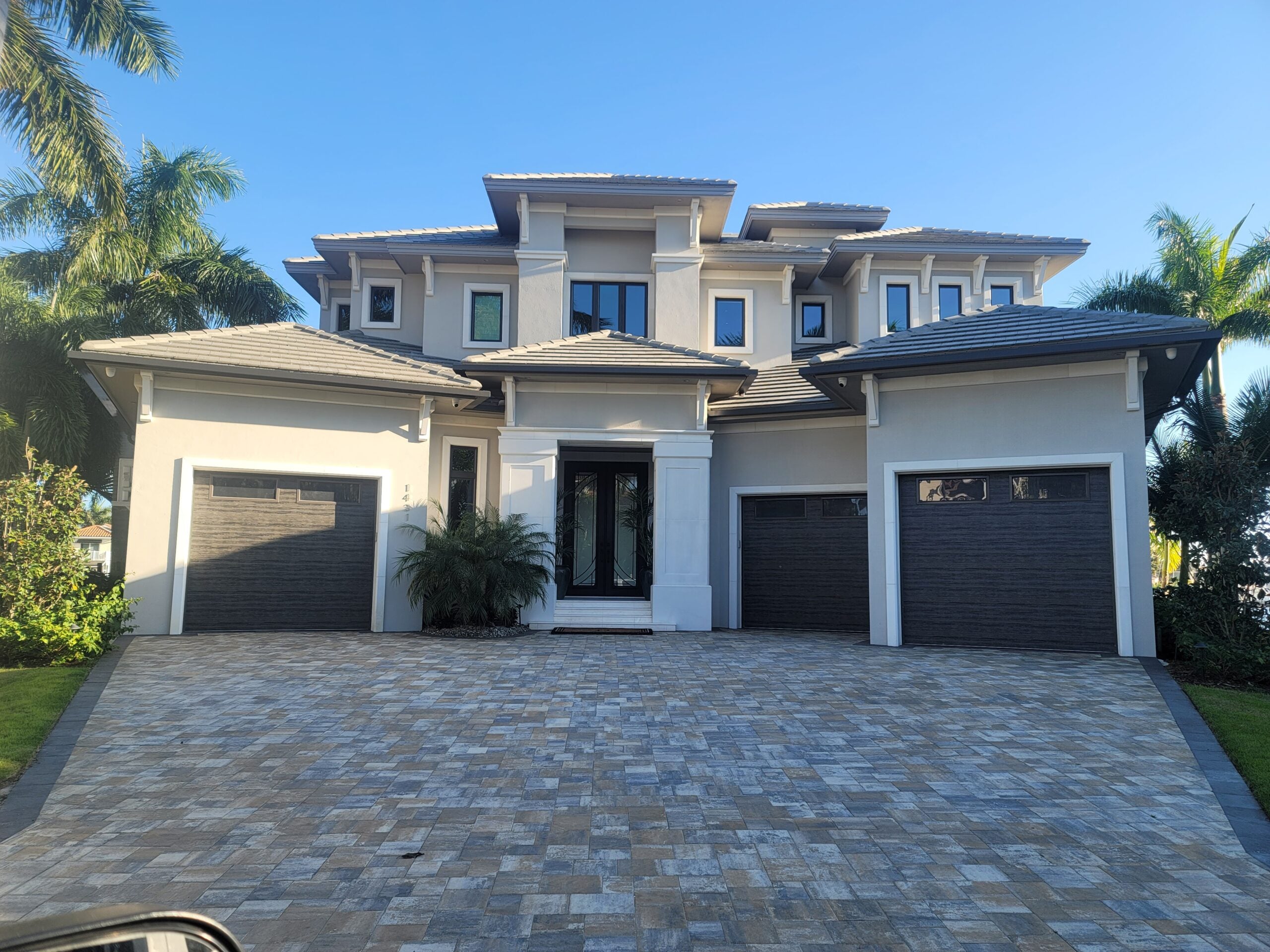 Two-story modern coastal home with paver driveway and double garage