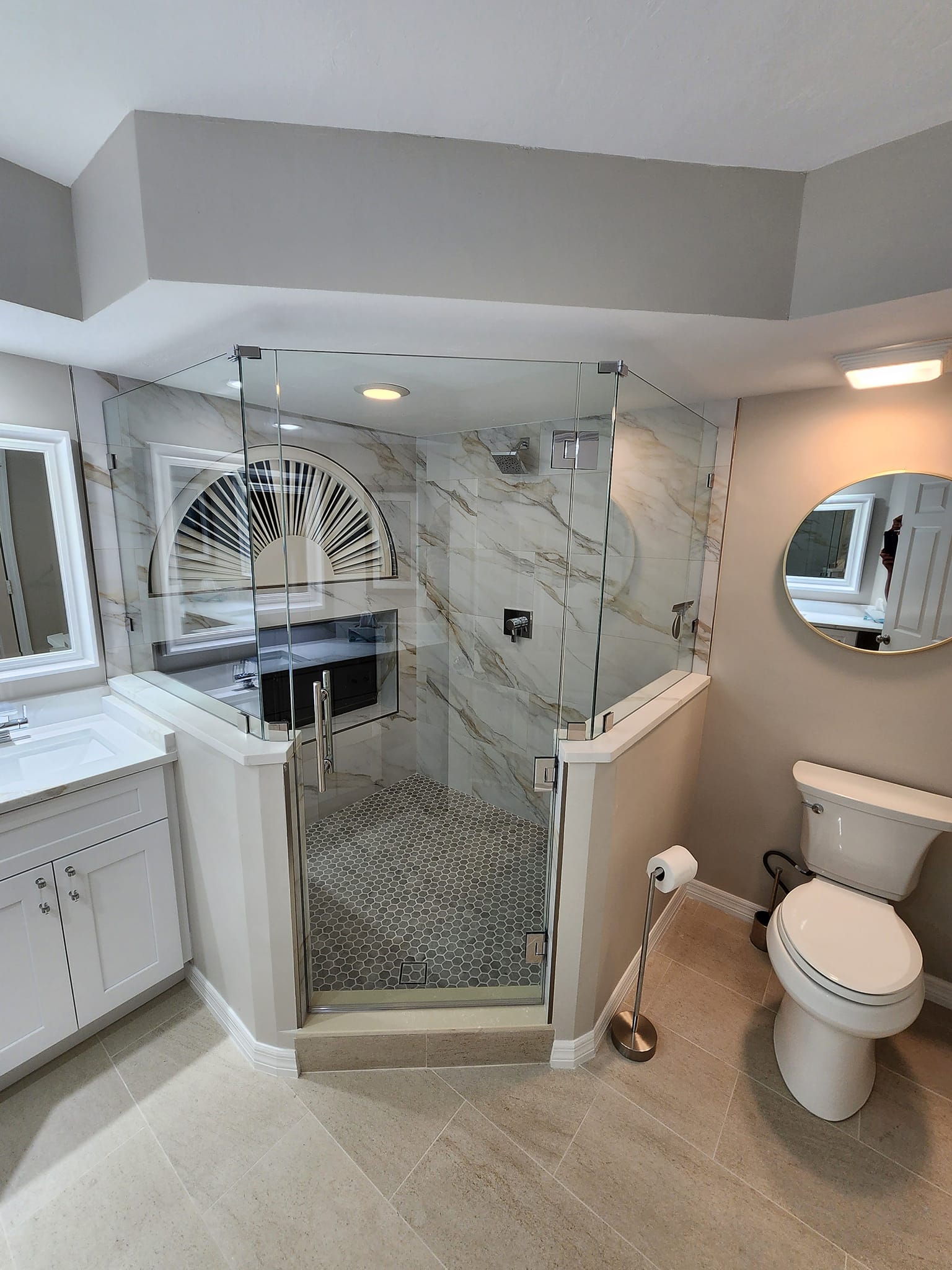Bathroom renovation with marble shower walls, hex tile floor, and double vanity
