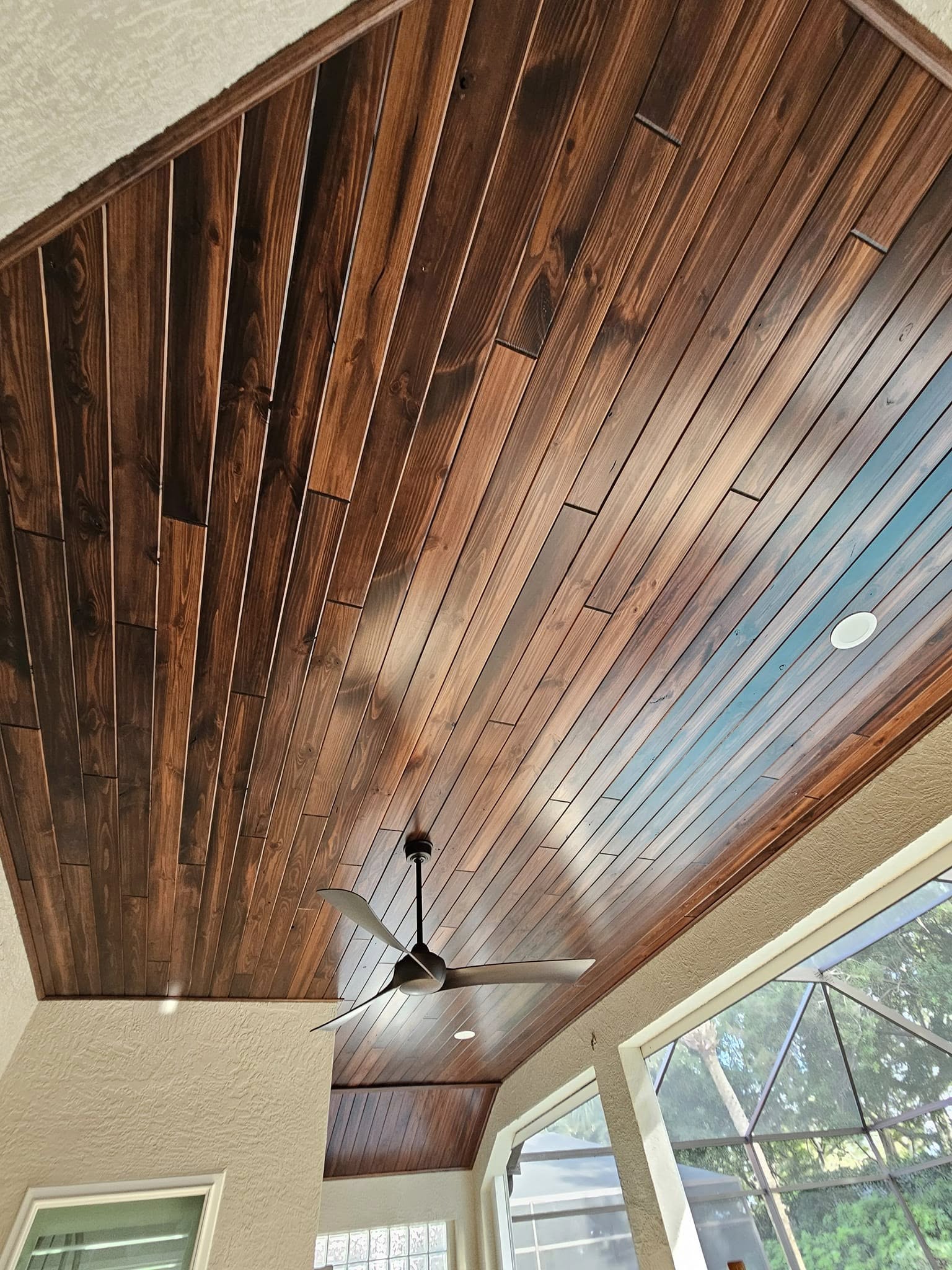 Wood-plank vaulted ceiling on a covered lanai with ceiling fan