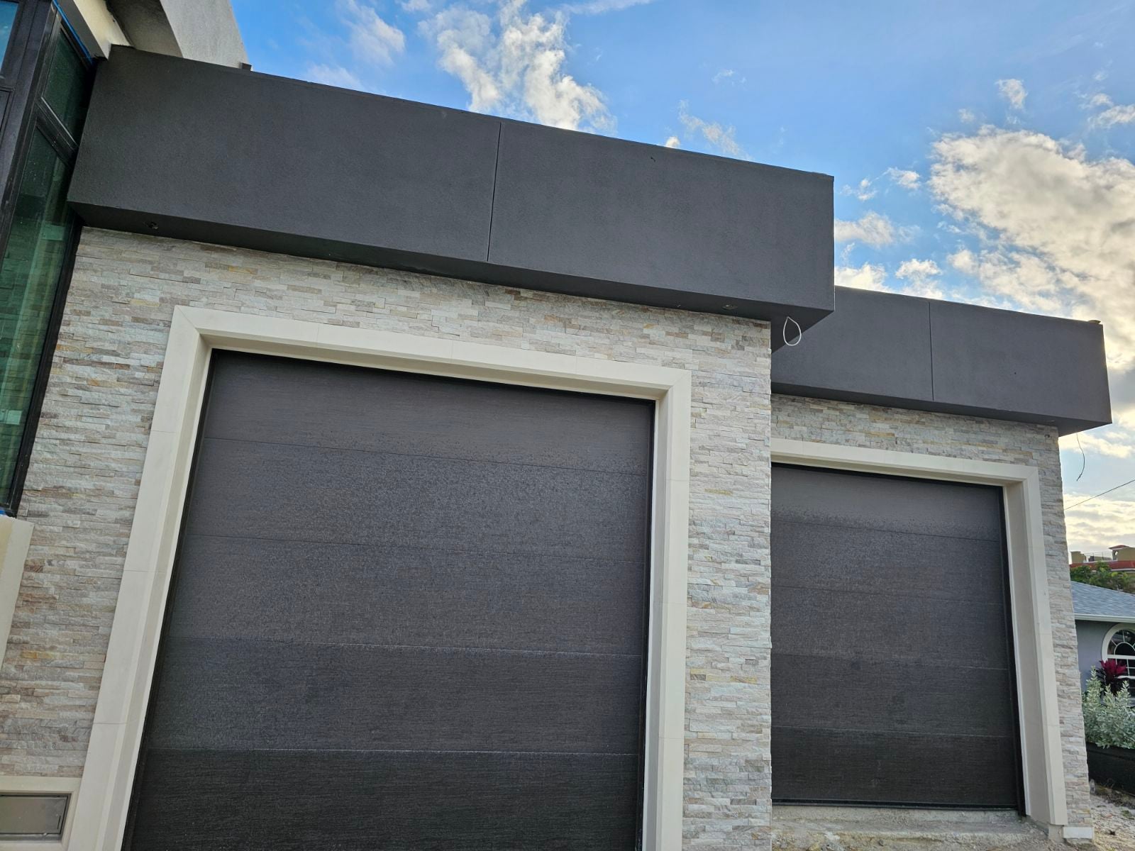 Modern home garage with stacked-stone facade and dark precast bands